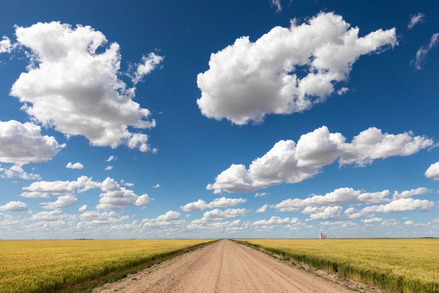 A dirt road under a wide Kansas sky